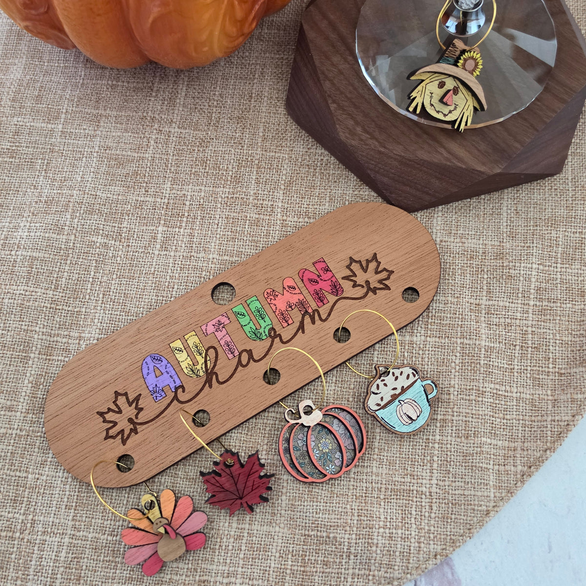 Autumn wine charms displayed on engraved wooden storage holder