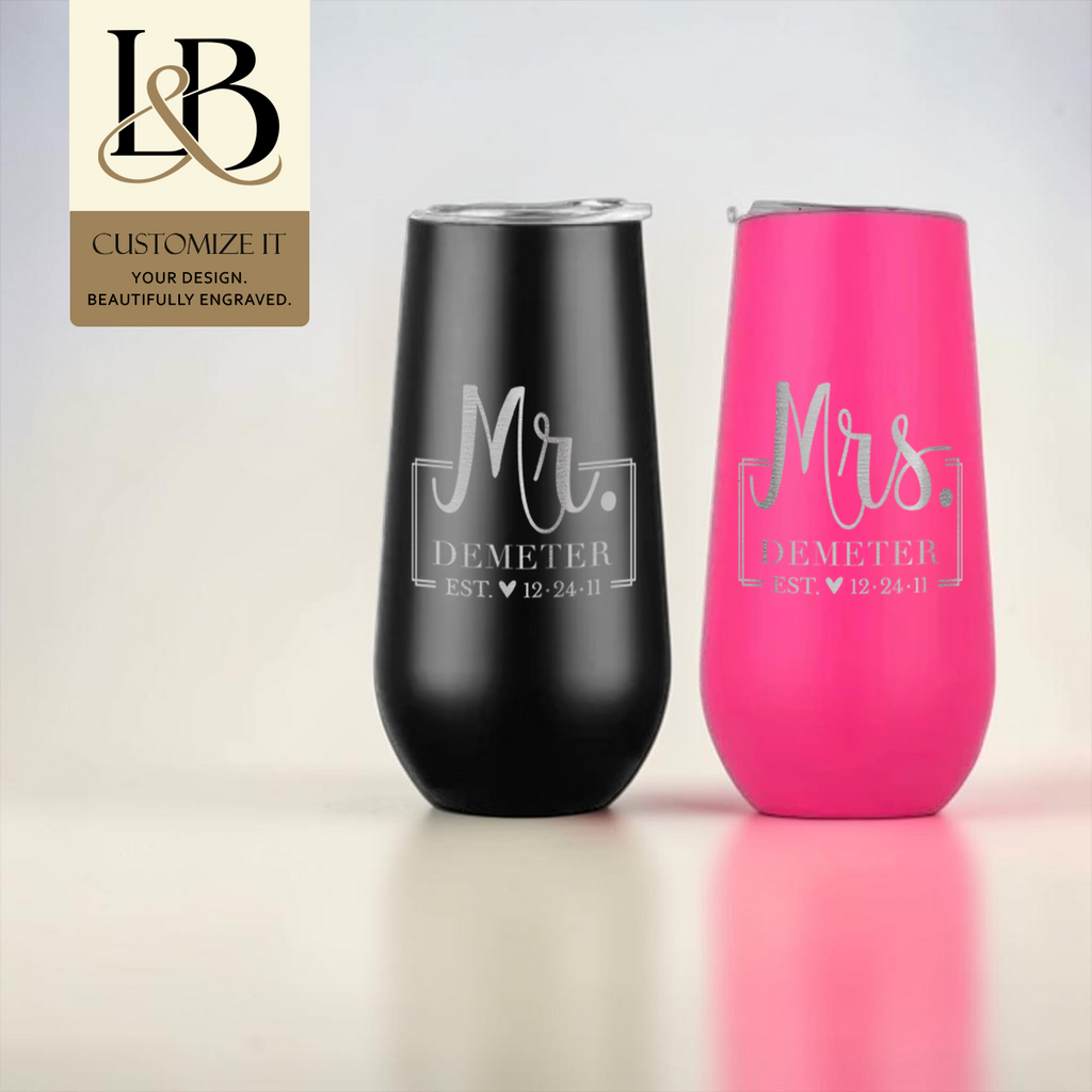 Black Mr. and pink Mrs. personalized stemless flutes with a gold brand badge against a pale background.