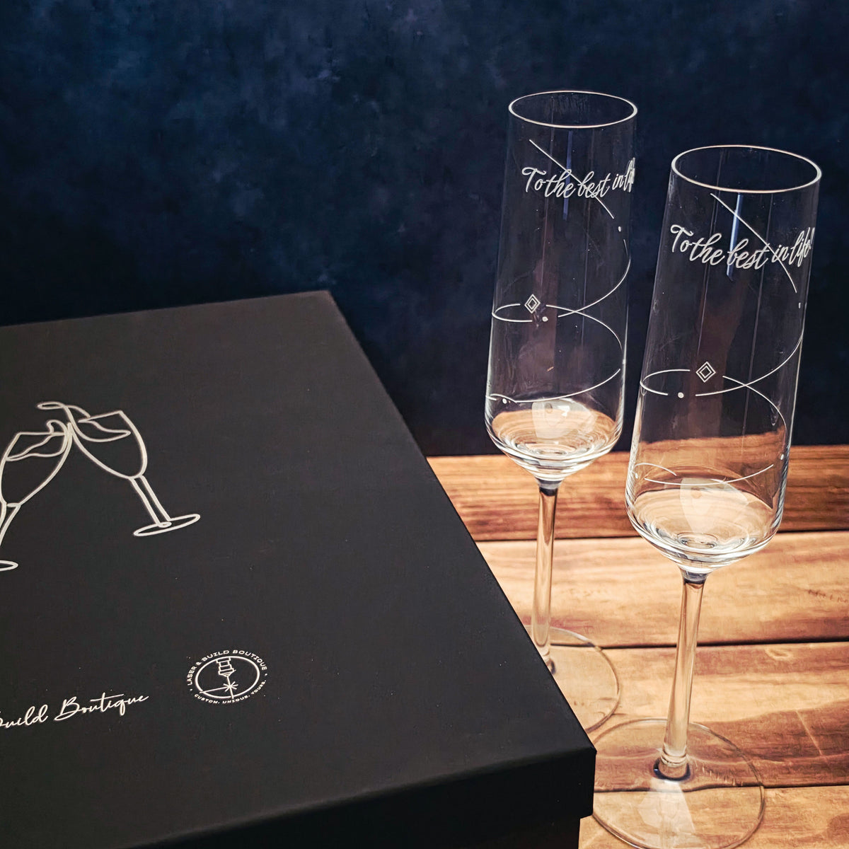 Detailed view of swirling engraving and To the best in life lettering on champagne glass