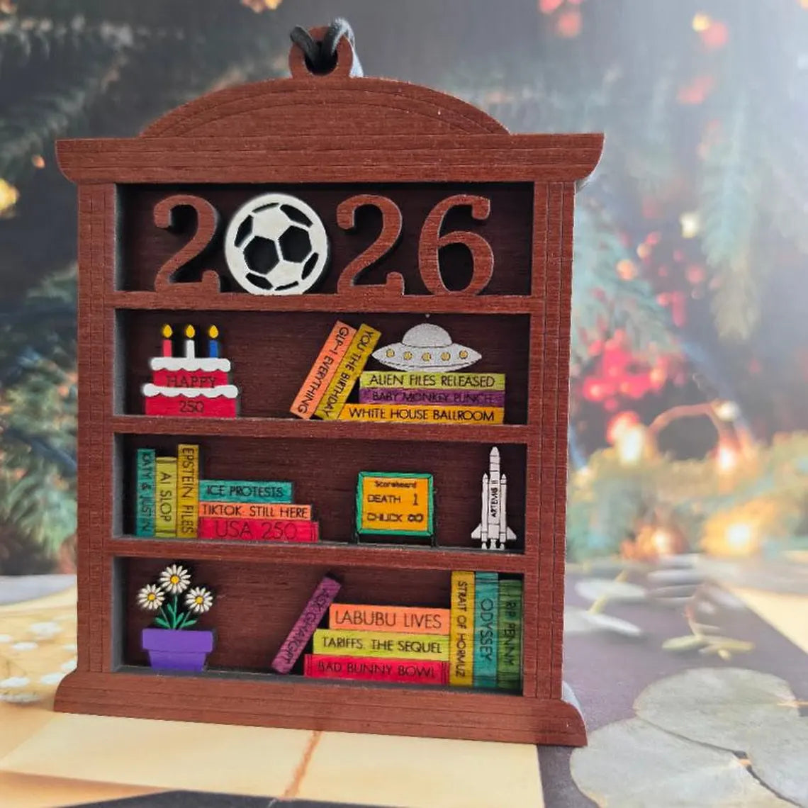 Hand painted 2026 bookshelf ornament featuring miniature books and memorable events from the year