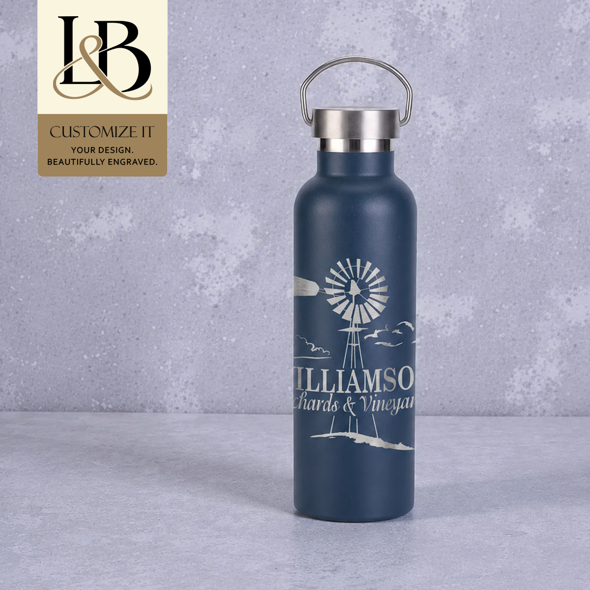 Navy Williamson wine growler with silver loop cap and gold brand badge against pale gray.