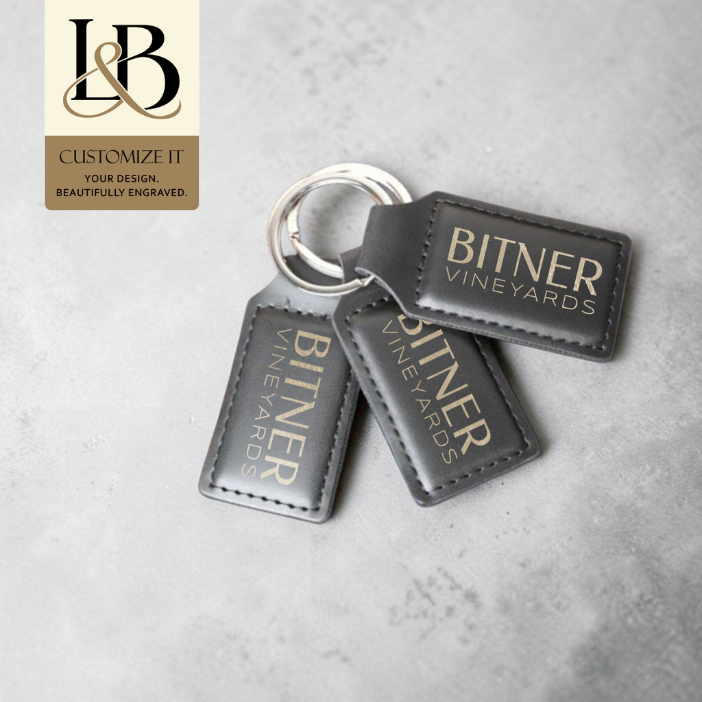 Three black Bitner Vineyards rectangular keychains with engraved lettering and a gold brand badge.