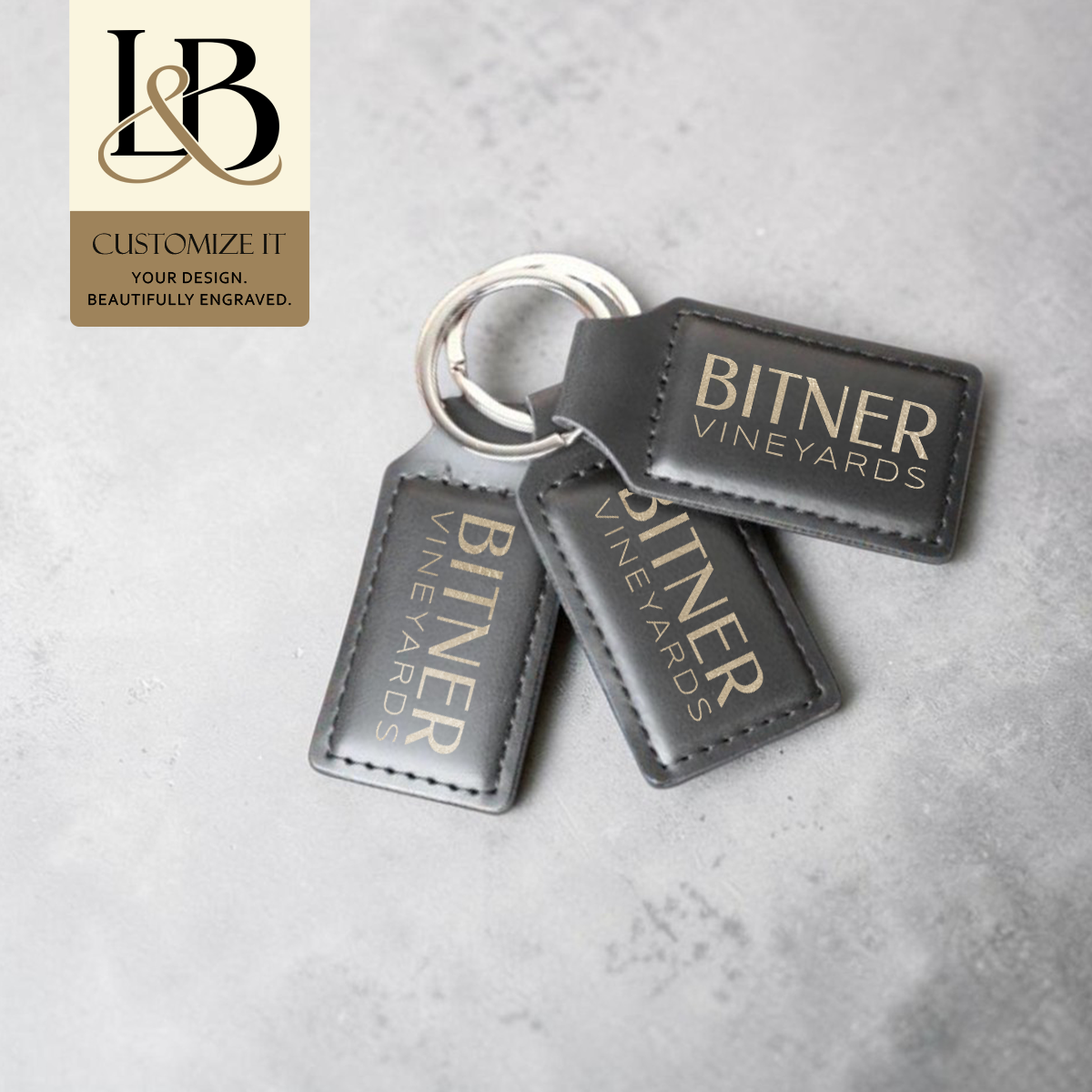 Three black Bitner Vineyards rectangular keychains with engraved lettering and a gold brand badge.